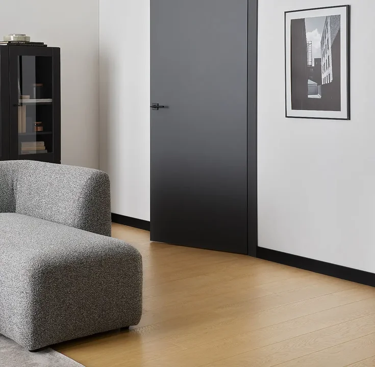 Stylowy salon z kontrastującą czarną listwą przypodłogową i jasną podłogą.